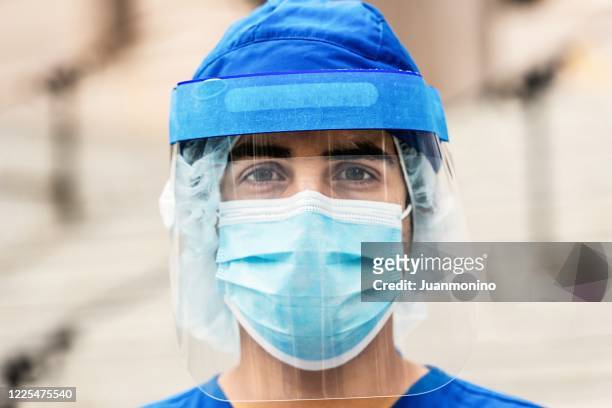 young serious overworked, male young health care worker looking at the camera - protective workwear stock pictures, royalty-free photos & images