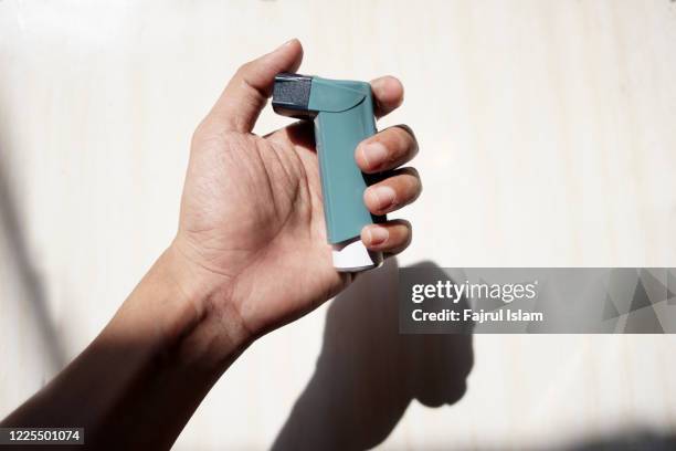 asthma inhaler on hand - reliever asthma inhaler stock pictures, royalty-free photos & images