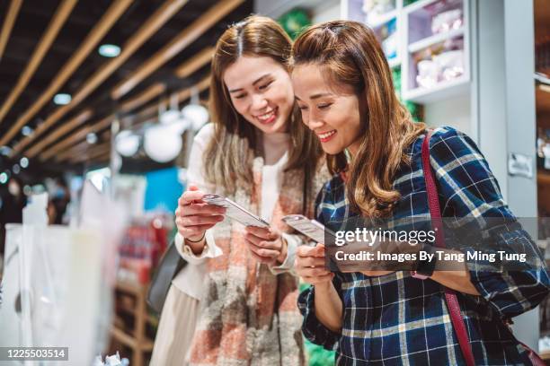 portriat of young cheerful girlfriends shopping for organic cosmetic products in a department store joyfully - beautiful asian student stock pictures, royalty-free photos & images