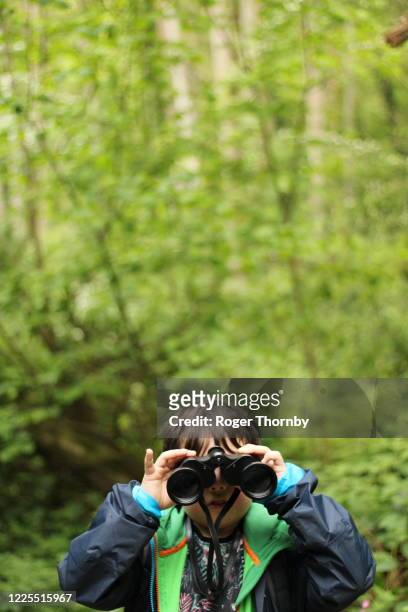 a young child looking at the camera with binoculars - spy hunter stock pictures, royalty-free photos & images