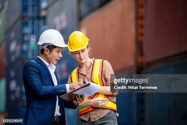 shipper and inspector discuss together over a clipboard at commercial dock. tracking and tracing at cargo container. freight forwarder business. - boat helm stock-fotos und bilder