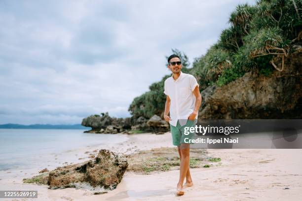 man walking on tropical beach, japan - blue shorts ストックフォトと画像