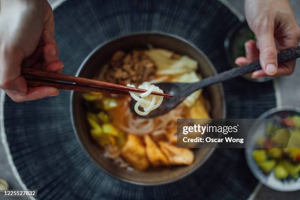 flat lay shot of human hands with chopsticks, eating a bowl of asian noodle soup - thailändische küche stock-fotos und bilder