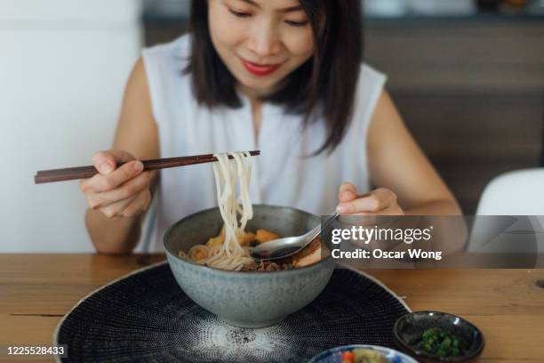 young asian woman eating a bowl of fresh noodle soup with chopsticks - female eating chili bildbanksfoton och bilder