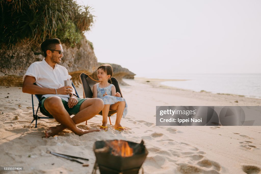 Father and daughter enjoying beach campsite at sunset, Okinawa, Japan