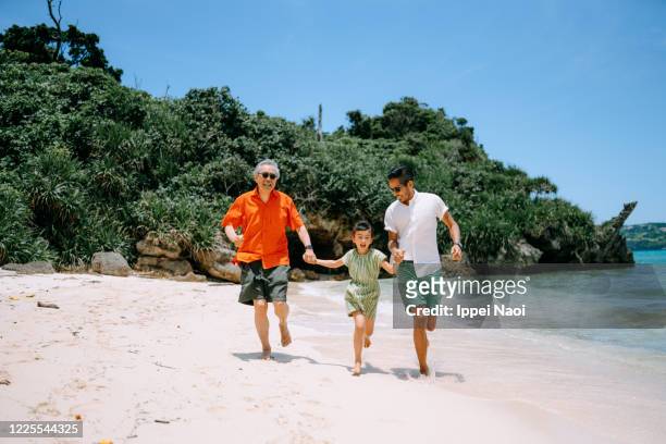 three generation family running together on tropical beach - 家族　日本人　走る ストックフォトと画像