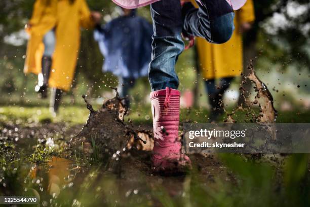 unrecognizable child running through muddy puddle in nature. - mud stock pictures, royalty-free photos & images