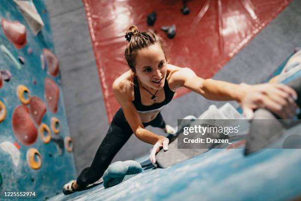 hoge hoekmening van sterke vrouw op kei het beklimmen - boulderen stockfoto's en -beelden