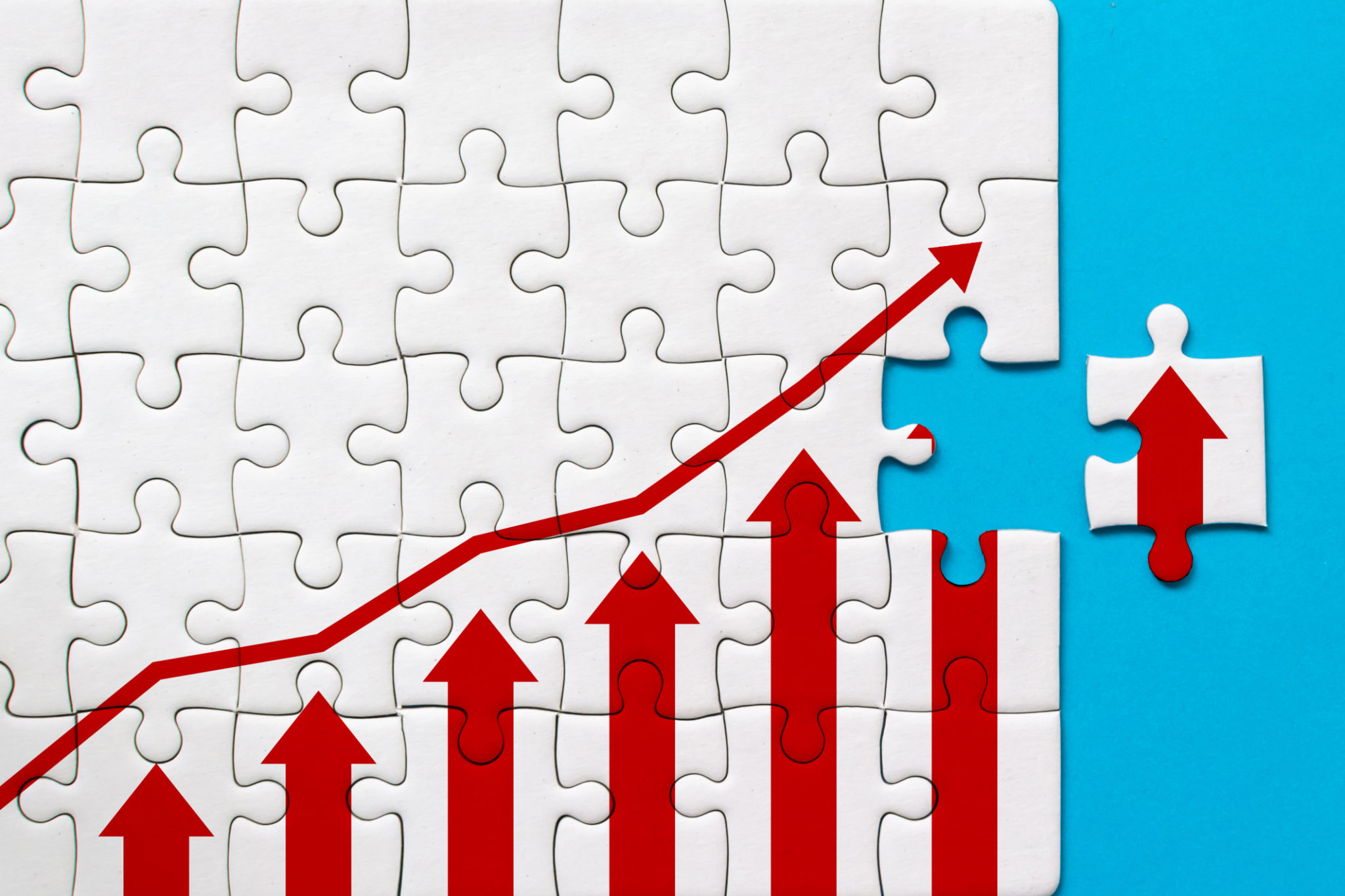 White jigsaw puzzle and graph arrow growth up on blue background. Business growth success process concept White jigsaw puzzle and graph arrow growth up on blue background. Business growth success process concept