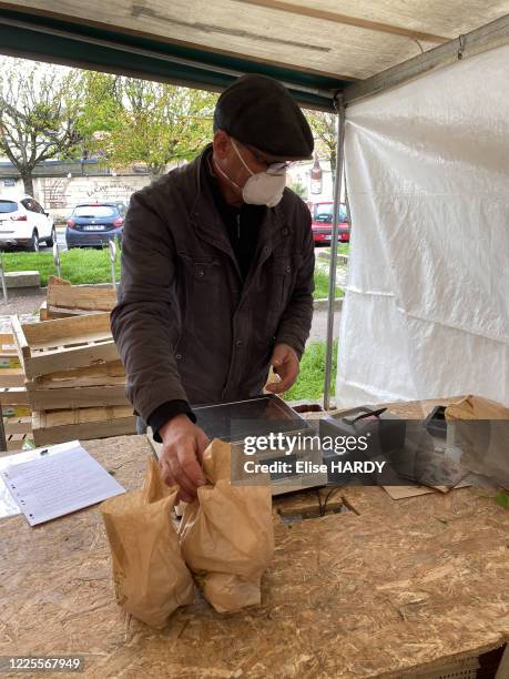 Marchand pesant les légumes avec un masque pour se protéger contre le Covid-19 au marché de Saint-Maur-des-Fossés, France, le 21 mars 2020.