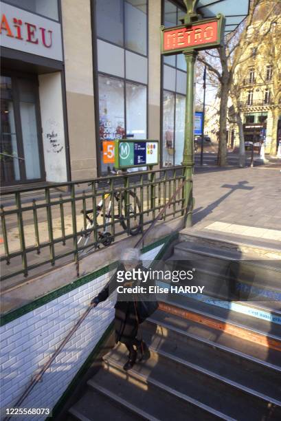 Femme âgée avec un masque empruntant les escaliers du métro "République" lors du confinement dû au coronavirus à Paris, France, le 28 mars 2020.