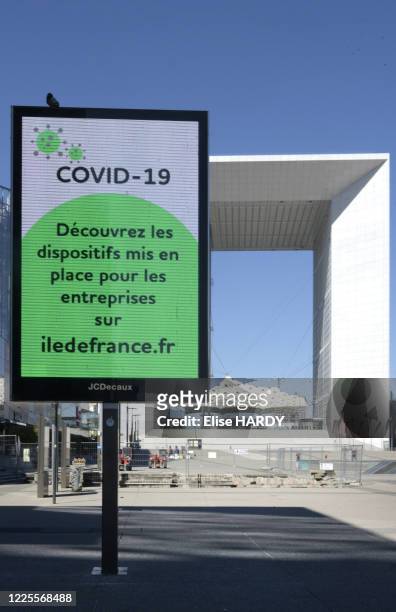 Panneau d'affichage "COVID-19 Découvrez les dispositifs mis en place pour les entreprises sur iledefrance.fr" dans le quartier de la Défense vide...