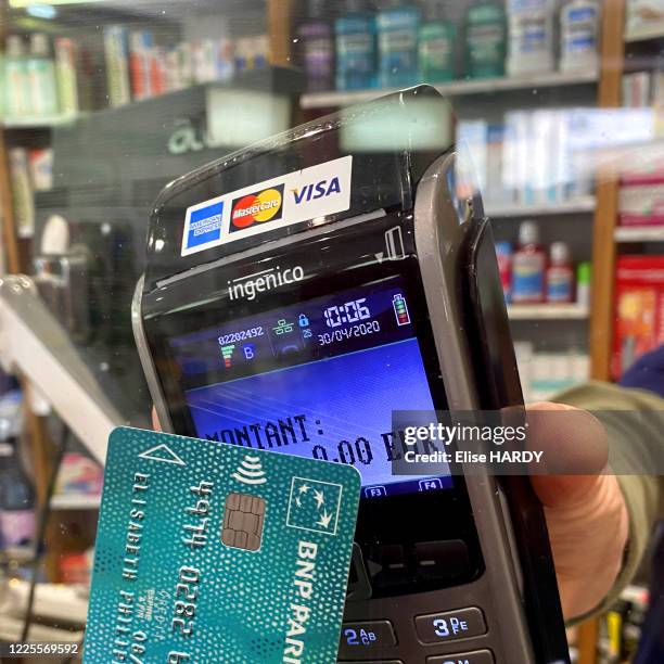 Paiement avec la carte bancaire à travers un plexiglass dans une pharmacie lors du confinement suite au coronavirus à Saint-Maur-des-Fossés, France,...