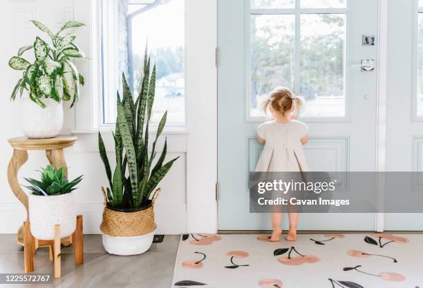 little girl looking out the door - house entrance interior stock pictures, royalty-free photos & images