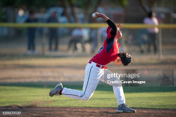 teen baseball player pitching in red uniform in wind up on the mound - baseball pitchers mound - fotografias e filmes do acervo