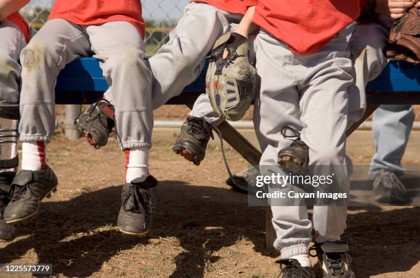 boys legs intertwined on a baseball bench - t ball game stock pictures, royalty-free photos & images