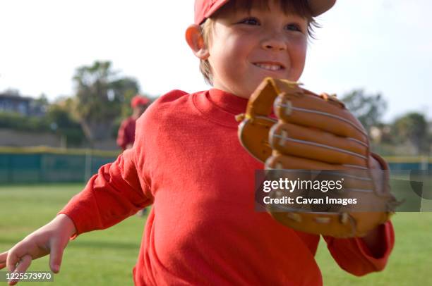 close up of young boy running off the tball fiels with a big smile - eternal youth stock pictures, royalty-free photos & images