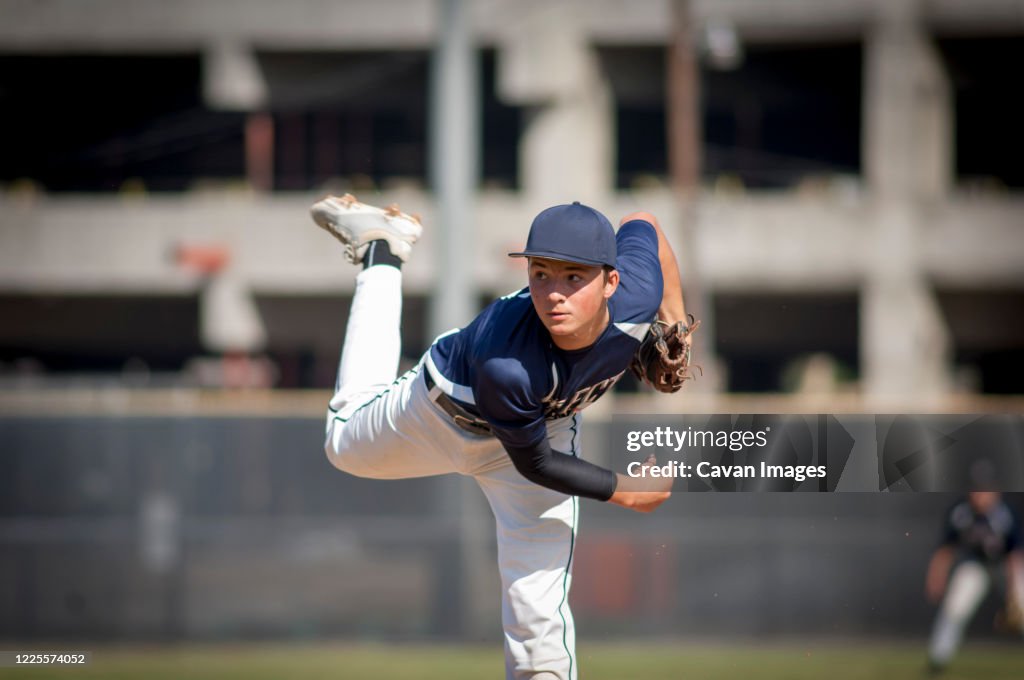Teen baseball player pitcher in blue uniform on the mound