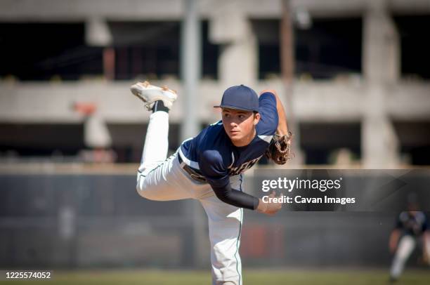 teen baseball player pitcher in blue uniform on the mound - kid baseball pitcher stock pictures, royalty-free photos & images