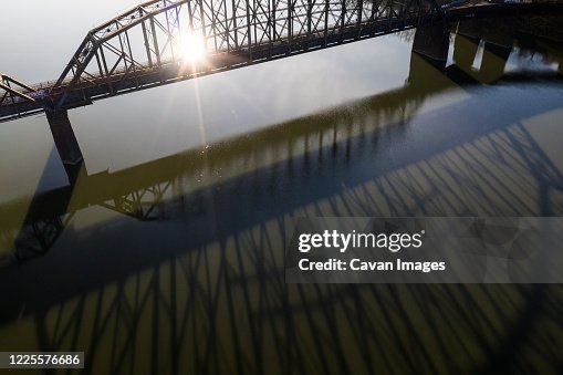 Bridge Casts Long Shadow on River During Sunrise