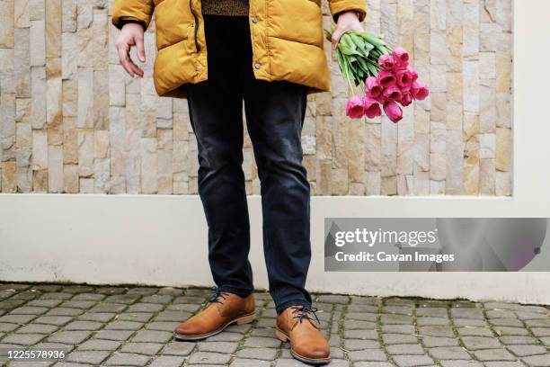 blond man in a yellow winter jacket with a bouquet of tulips in hands - israeli military stock pictures, royalty-free photos & images