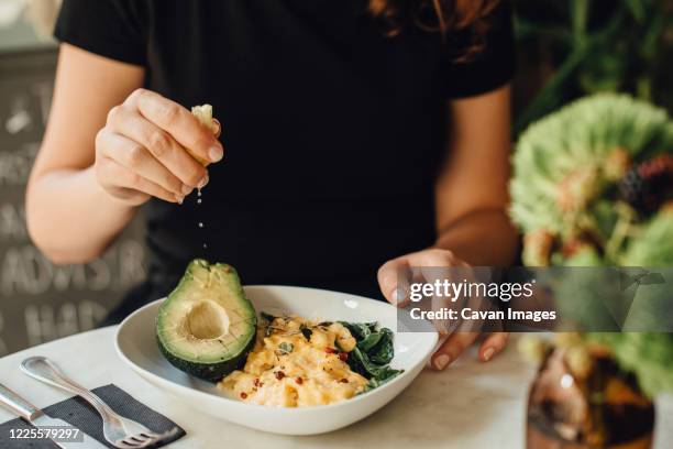 midsection of woman eating scrambled eggs and avocado for breakfast - ovo mexido imagens e fotografias de stock