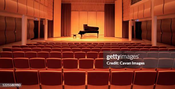 image of a piano on stage inside an empty concert hall - konzertsaal stock-fotos und bilder