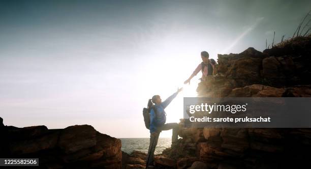 couple hikers climbing up  mountain cliff . helps and team work concept. - berg klimmen team stockfoto's en -beelden