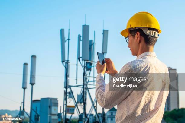 engineer holding mobile phone testing the communications tower - transportation building type of building stock pictures, royalty-free photos & images