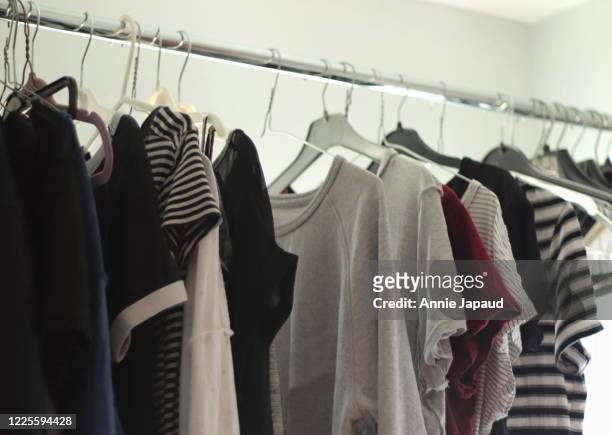 fresh laundry drying out on hangers in laundry room, clothes with pale colours - drying stockfoto's en -beelden