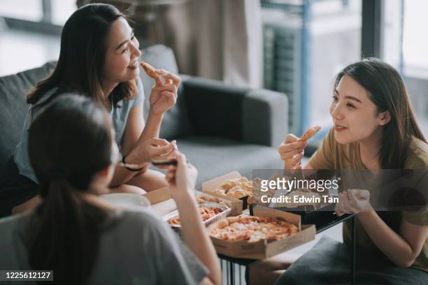 3 asian chinese female friends having pizza for lunch in their living room bonding time - woman junk food eating stock pictures, royalty-free photos & images