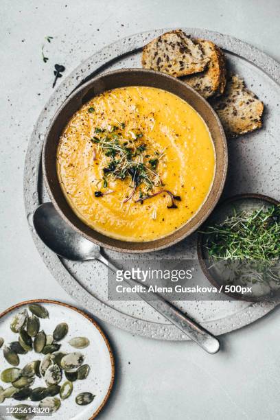 still life with pumpkin soup in bowl served with bread, pumpkin seedlings and sprouts, russia - pumpkin soup stock-fotos und bilder