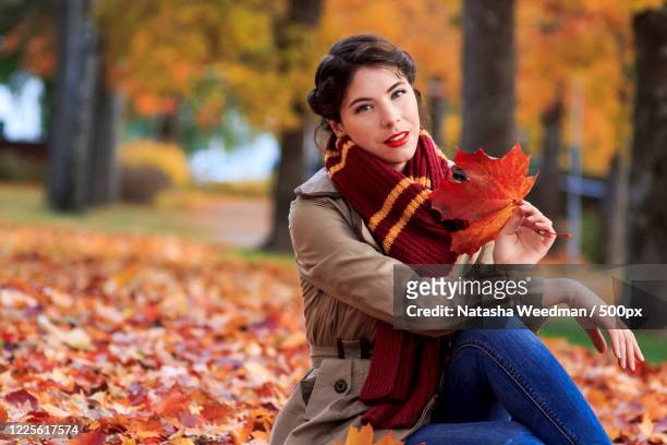 portrait of woman sitting on autumn leaves in prak,porvoo, finland - porvoo stockfoto's en -beelden