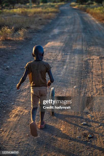 ragazzo africano gioca con una ruota sulla savana, africa orientale - village boy foto e immagini stock