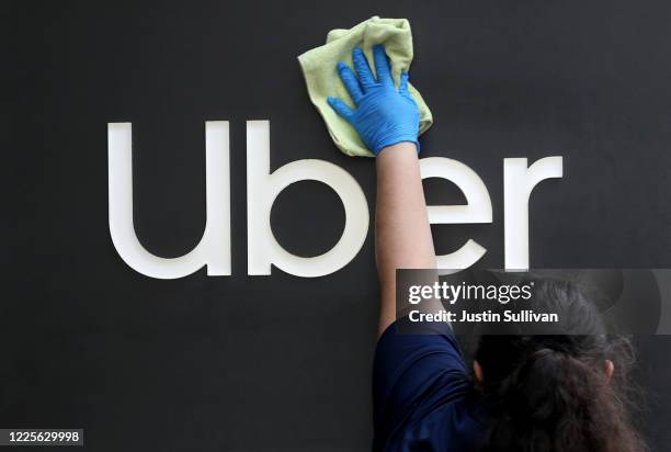 Worker cleans a sign in front of the Uber headquarters on May 18, 2020 in San Francisco, California. Uber announced plans to cut 3,000 jobs and...