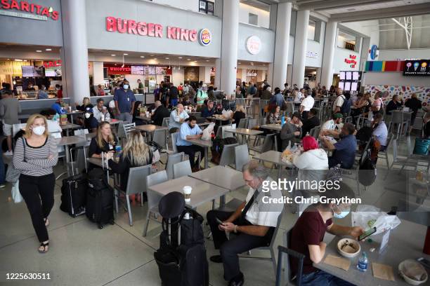 Passengers sit at the food court between terminals at Charlotte Douglas International Airport on May 15, 2020 in Charlotte, North Carolina. Air...