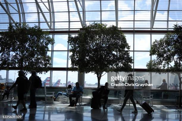 Passengers walk between terminals at Charlotte Douglas International Airport on May 15, 2020 in Charlotte, North Carolina. Air travel is down an...