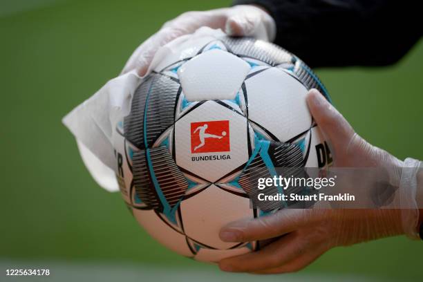 An employee of Werder Bremen disinfects an official match ball ahead of the Bundesliga match between SV Werder Bremen and Bayer 04 Leverkusen at...