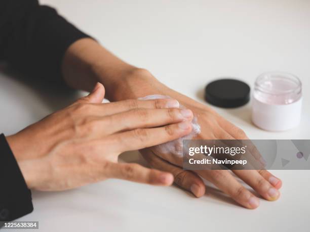 applying moisturising hand cream - handrücken stock-fotos und bilder