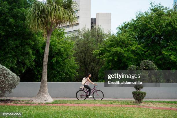 alltagsjunge frau fährt fahrrad in der nähe von bäumen - monterrey mexico stock-fotos und bilder