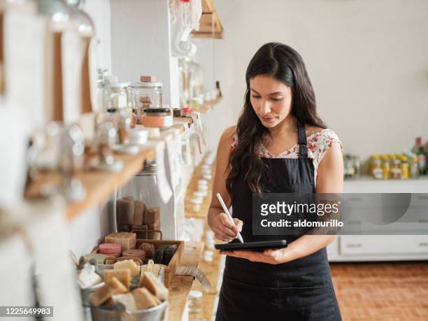 hispanic female employee making inventory in sustainable shop - product owner stock pictures, royalty-free photos & images
