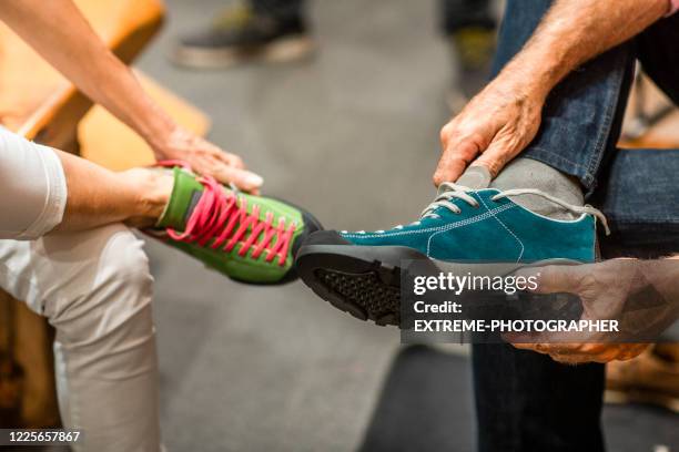 two people trying on a model of climbing shoes in a shop - sportswear shop stock pictures, royalty-free photos & images
