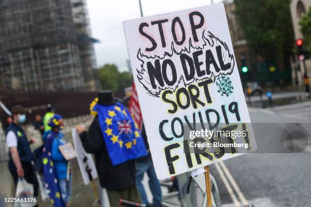 Placard reading "Stop No Deal Sort Covid19 First!" stands near anti-Brexit protesters outside the Houses of Parliament in London, U.K., on Wednesday,...