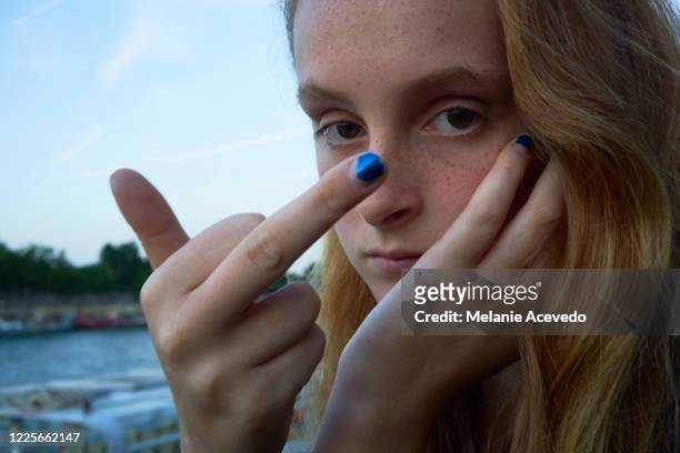 close-up portrait of a teenage girl with long red hair brown eyes and freckles looking at and giving the camera the finger. - giving a girl head fotografías e imágenes de stock