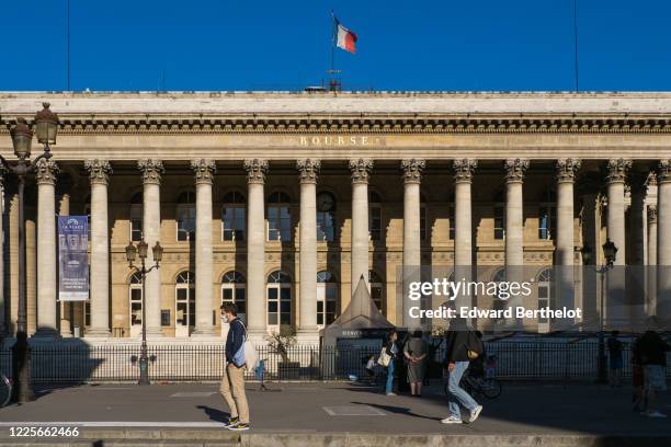 Passerby wears a protective face mask in front of the Palais Brongniart, formerly "Palais de La Bourse", on May 18, 2020 in Paris, France. The...