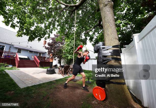 Zach Blumberg punches a homemade heavy bag he attached with duct tape to a tree in his backyard on May 18, 2020 in Oceanside, New York. Blumberg, an...