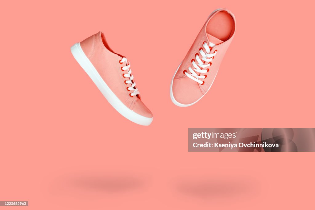 White sneakers with purple laces on yellow background. Modern minimal fashion art trendy bold color still life