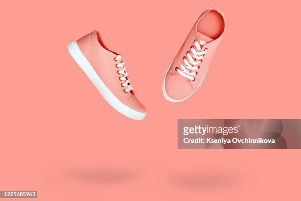 white sneakers with purple laces on yellow background. modern minimal fashion art trendy bold color still life - footwear stock pictures, royalty-free photos & images