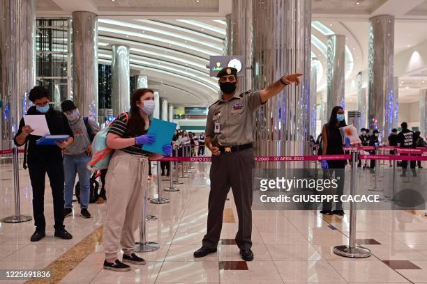 An Emirati policeman directs a tourist to get a medical screening upon arrival at Teminal 3 at Dubai airport, in the United Arab Emirates, on July 8...