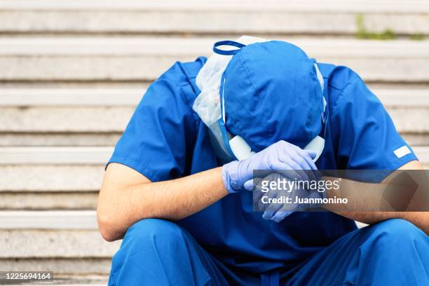 serious, overworked, very sad male health care worker - state of emergency stock pictures, royalty-free photos & images